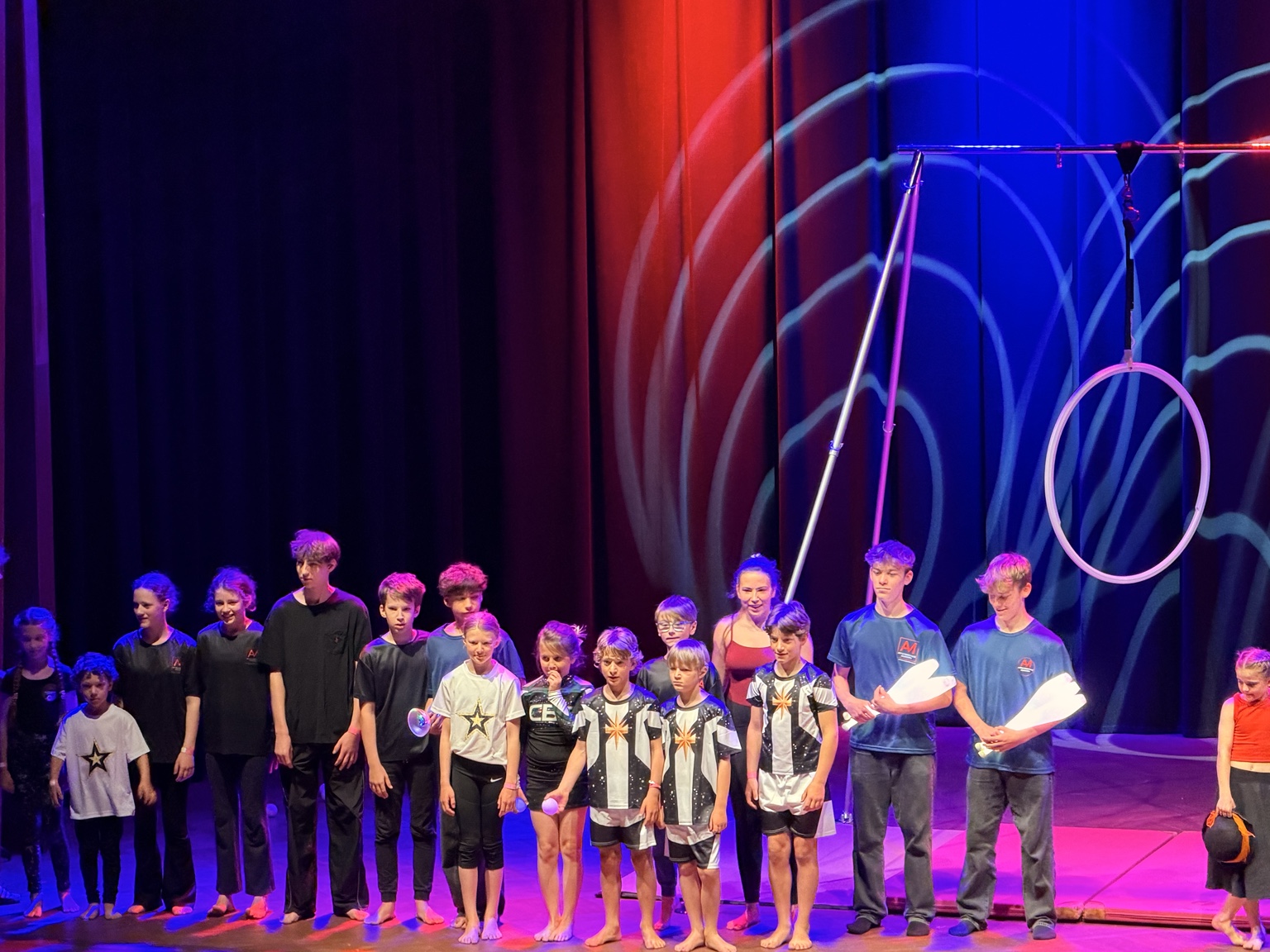 Jeunes artistes réunis sur scène avec des accessoires de jonglage et un cerceau aérien